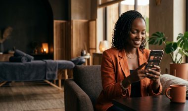 A smiling woman in a Nairobi wellness lounge uses a smartphone app to book a massage.