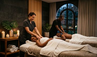 A couple receives synchronized massages in a softly lit private spa room.